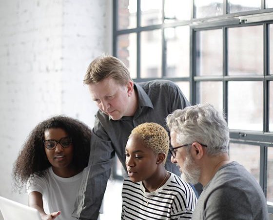 A group of people sitting around a laptop.